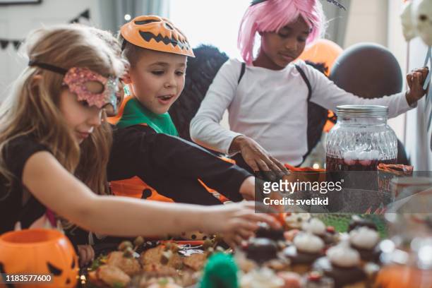 bambini che mangiano alla festa di halloween - halloween kid foto e immagini stock