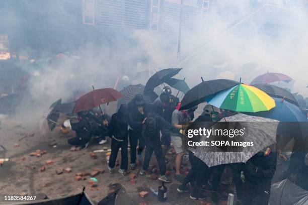 Protesters take cover behind their umbrellas during the demonstration. Police surround the Polytechnic University after pro-democratic protesters...