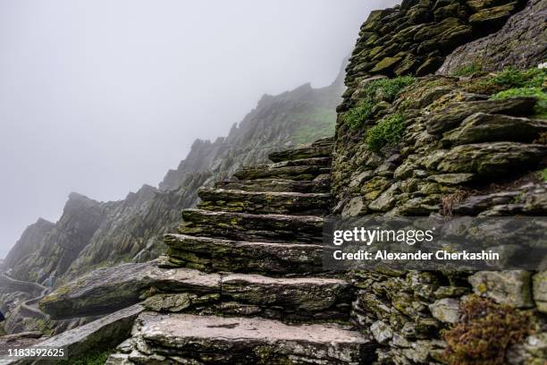 steep stone steps on the edge of ancient trail with ragged cliffs in the background in the dense fog. - skellig michael 個照片及圖片檔