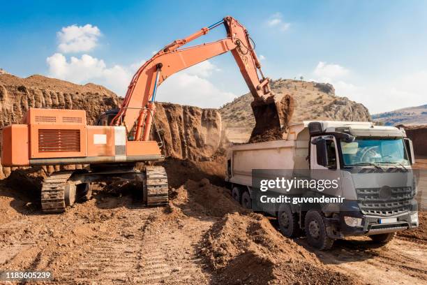 excavator loading dumper trucks at sunset - dirt gravel stock pictures, royalty-free photos & images