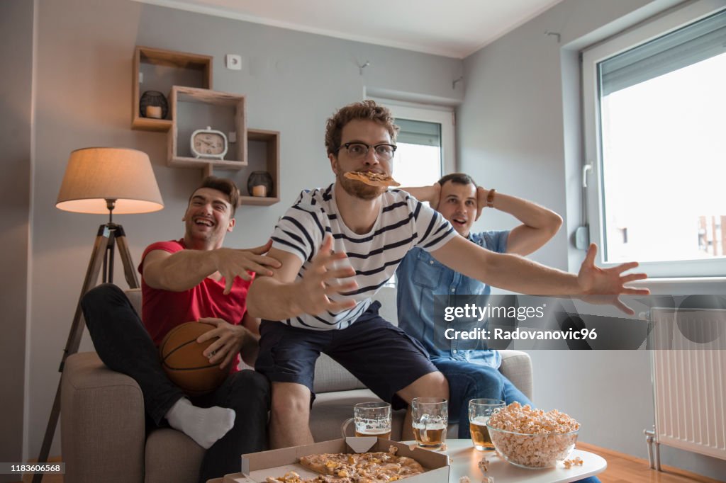 Group of friends watching basketball game and drinking beer