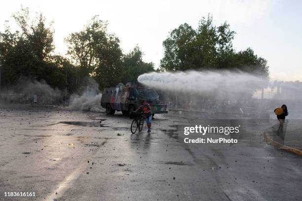 An anti-government demonstrator challenges a police water cannon spray during clashes with police in Santiago, Chile, Thursday, October 30, 2019.