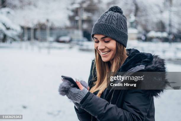 allegri giovane donna messaggi di testo - cappotto invernale foto e immagini stock