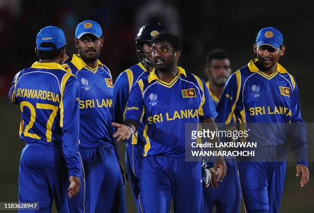 Sri Lankan cricketer Muttiah Muralitharan is congratulated by his teammates after dismissing unseen Canadian cricketer Balaji Rao during the Group A...