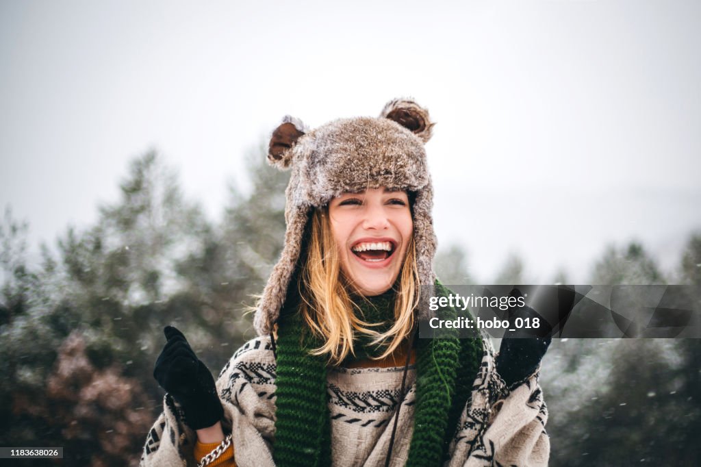 Fröhliche junge Frau genießt kalten Wintertag in den Bergen