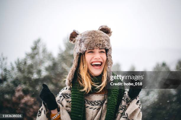 joven alegre disfruta del frío día de invierno en las montañas - gorro navidad fotografías e imágenes de stock