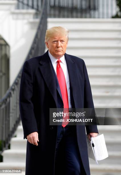 President Donald Trump holds his notes as he talks to the media on the South Lawn of the White House before boarding Marine One in Washington, DC,...