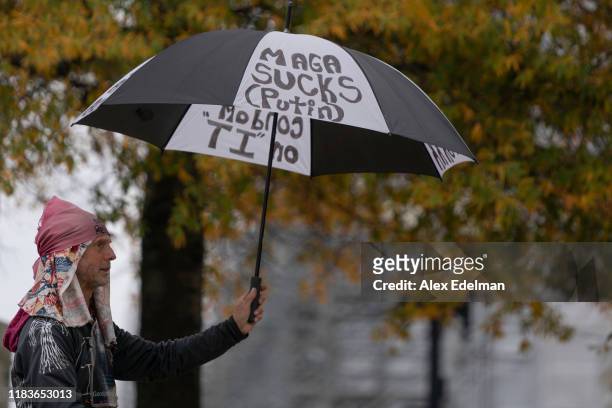 Demonstrator holds up an umbrella with anti-Trump slogans written on it as Gordon Sondland, the U.S ambassador to the European Union, testifies...