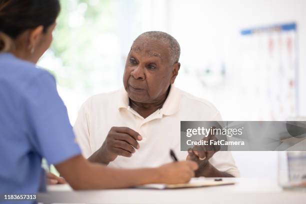 ein älterer herr in seinem arztbüro erhält ein check-up-stockfoto - gerontology stock-fotos und bilder