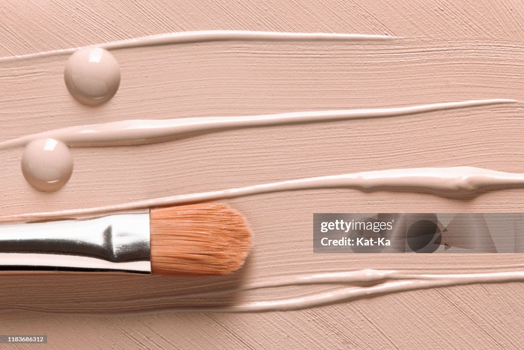 Makeup background. Liquid foundation texture and cosmetic brush