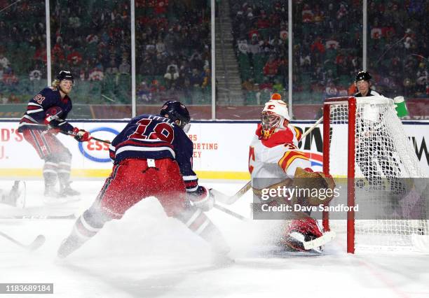 Bryan Little of the Winnipeg Jets scores the game-winning goal against goaltender David Rittich of the Calgary Flames as Derek Ryan looks on in...