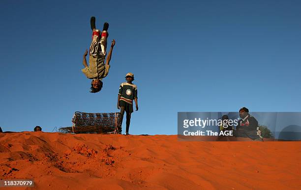 Darren Long takes a dive off an old mattress on the outskirts of Imanpa where the Federal Government has begun rolling out its changes to the...