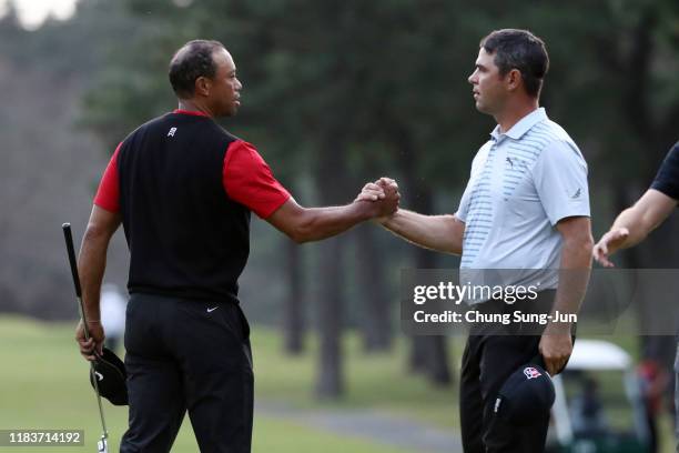 Tiger Woods and Gary Woodland of the United States shake hands on the 11th green after the game is suspended during the final round of the Zozo...