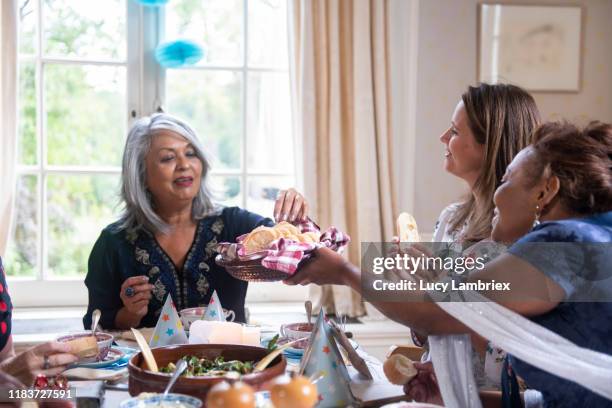 mixed group of women having a vegan birthday lunch party: serving bread to the birthday girl - 40 birthday stock pictures, royalty-free photos & images