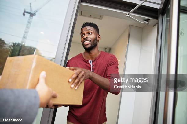 man receiving a parcel - receiving parcel stock pictures, royalty-free photos & images