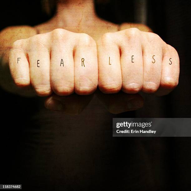 woman fists with fearless across the knuckles - knuckle stock pictures, royalty-free photos & images