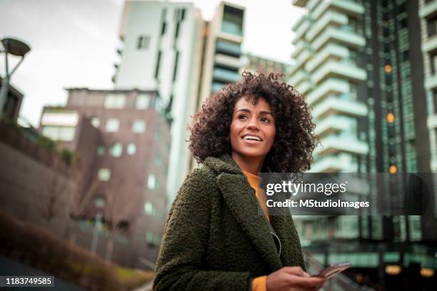 een lachende jonge vrouw in het centrum van de stad - wegkijken stockfoto's en -beelden