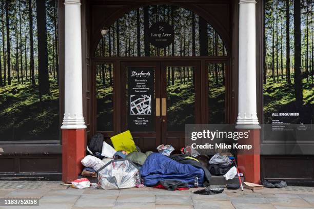 Homeless people sleeping rough in a doorway surrounded by an idillic picture of a natural forest landscape in Covent Garden in London, England,...