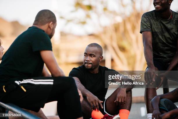 Cool sportsmen sitting around pre-match with one wearing bright orange socks