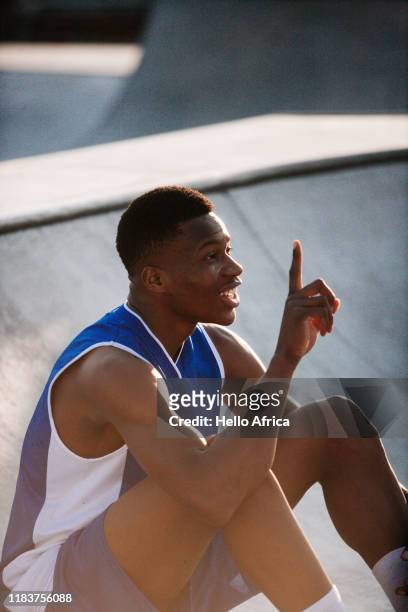 Happy smiling seated basketball player showing number one with his finger