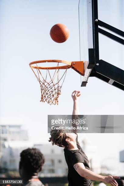 A basketball player reaches up as a ball makes it way to the hoop
