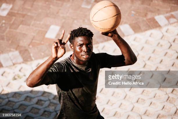 High angle shot of handsome basketball player showing Victory and holding ball
