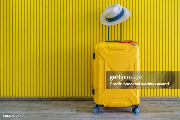 yellow suitcase with sun glasses and hat on yellow background. travel concept. minimal style - procedimiento judicial fotografías e imágenes de stock