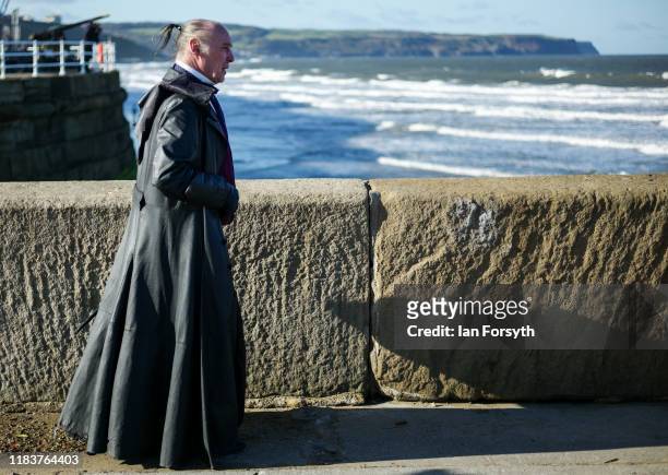 Man wearing a long leather coat walks along the pier during Whitby Goth Weekend on October 27, 2019 in Whitby, England. The Whitby Goth weekend began...
