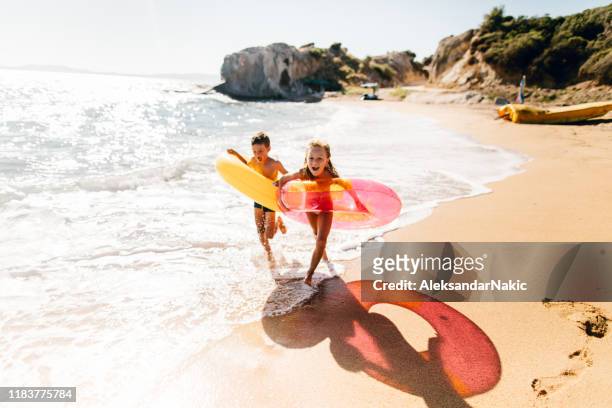 brother and sister enjoying summer morning at the beach - beach holiday stock pictures, royalty-free photos & images