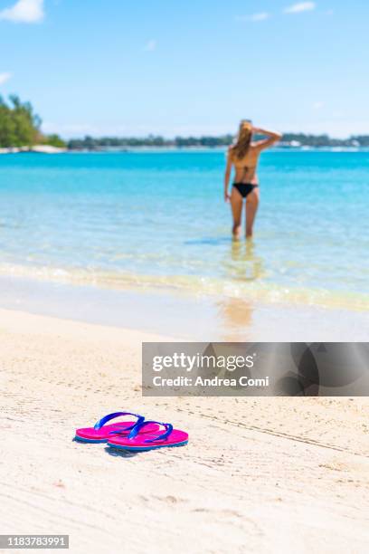 pair of flip-flops with a woman tourist in the background - wild coast stock-fotos und bilder