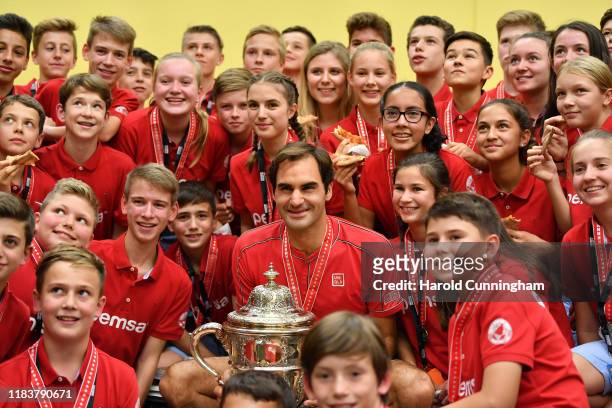 Roger Federer of Switzerland celebrates his victory with the tournament ball boys and girls during the pizza party following the final match of the...