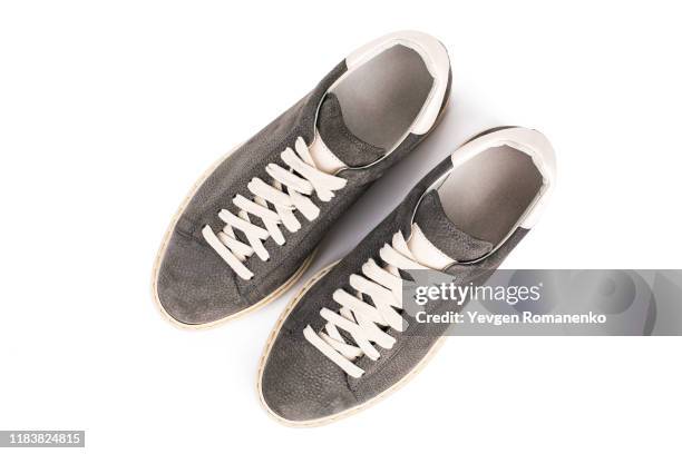 top view on grey suede sneakers shoes on white background, directly above view - suede shoe stock-fotos und bilder