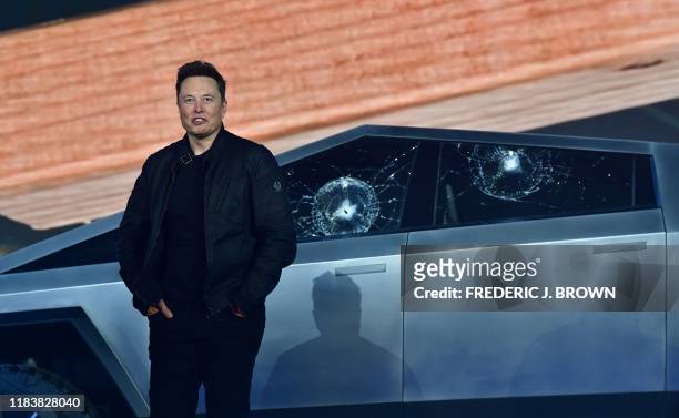 Tesla co-founder and CEO Elon Musk stands in front of the shattered windows of the newly unveiled all-electric battery-powered Tesla's Cybertruck at...