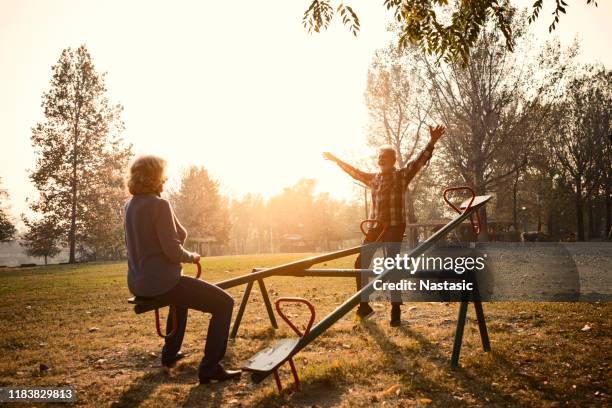 happy senior couple having fun at the playground ,riding seesaw - see saw stock pictures, royalty-free photos & images