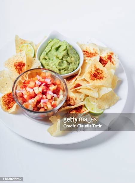 a plate of corn chips with guacamole and fresh salsa on white background - tortilla chip stock-fotos und bilder