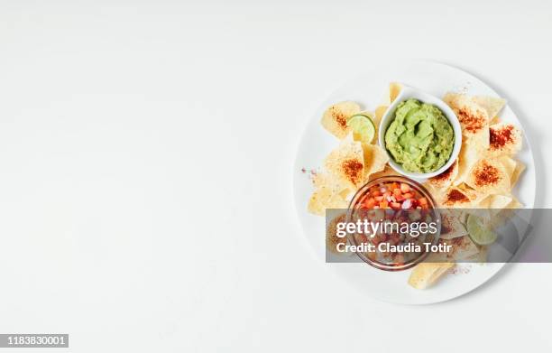 a plate of corn chips with guacamole and fresh salsa on white background - nachos - fotografias e filmes do acervo