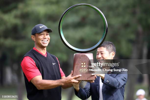 Tiger Woods of the United States receives the trophy from the Zozo founder Yusaku Maezawa at the award ceremony following the final round of the Zozo...