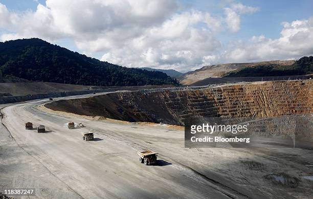 Haul trucks drive along a haulage road next to an open pit at the Batu Hijau copper and gold mine operated by PT Newmont Nusa Tenggara in Sumbawa,...