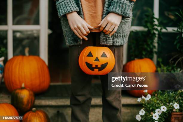 boy holding a halloween cup full of candies - bus eller godis bildbanksfoton och bilder