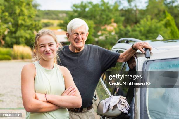 senior grandfather and his 13 year old grand daughter washing a car together in driveway - 12 year old blonde girl stock-fotos und bilder