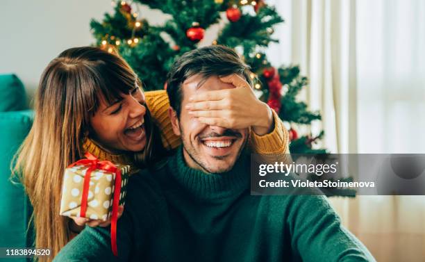 romantischejunges paar tauscht weihnachtsgeschenke aus - anbieten stock-fotos und bilder