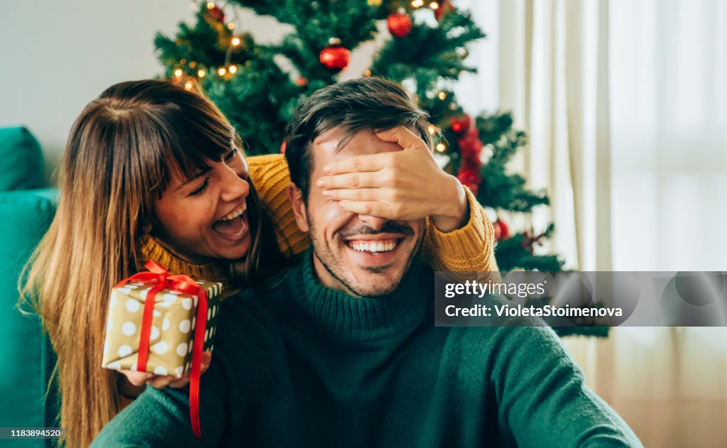 Romantic young couple exchanging Christmas gifts