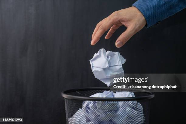 man's hand throwing crumpled paper in basket - flip flop stockfoto's en -beelden