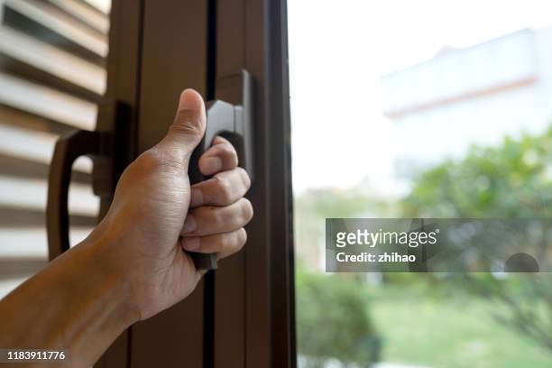 human hand touches the handle of the window - handle stock-fotos und bilder