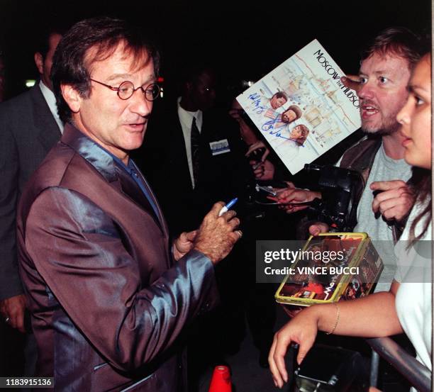 Academy Award winning actor Robin Williams signs autographs for fans as he arrives for the premiere of his new film, "What Dreams May Come" 28...