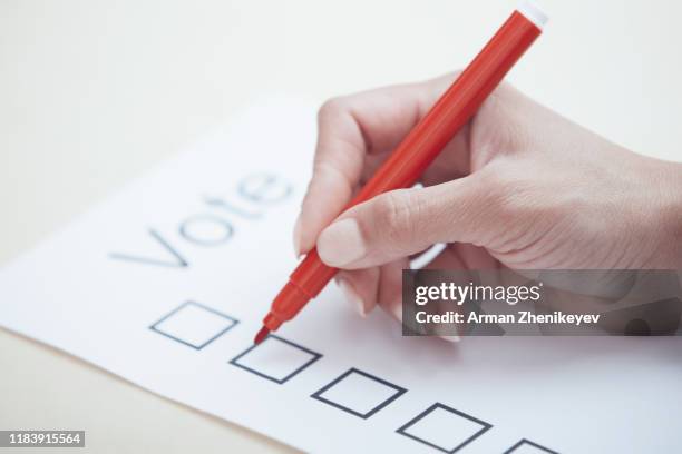 woman filling out voting document - election results stock-fotos und bilder