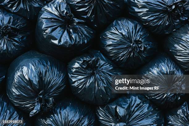 pile of black plastic garbage bags. - sac poubelle photos et images de collection