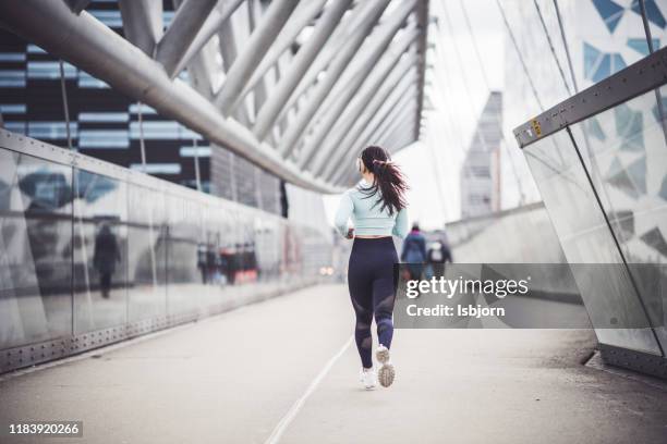 young beautiful woman running in the city center. - center athlete stock pictures, royalty-free photos & images