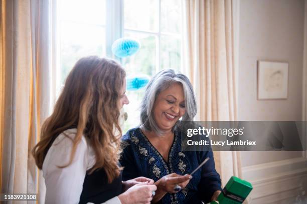 65 year old woman enjoying her present at her birthday - 65 year old asian women stockfoto's en -beelden