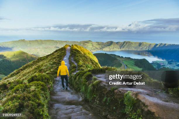 hiker with yellow raincoat in the viewpoint with volcanic crater in the azores islands. - azores stock pictures, royalty-free photos & images